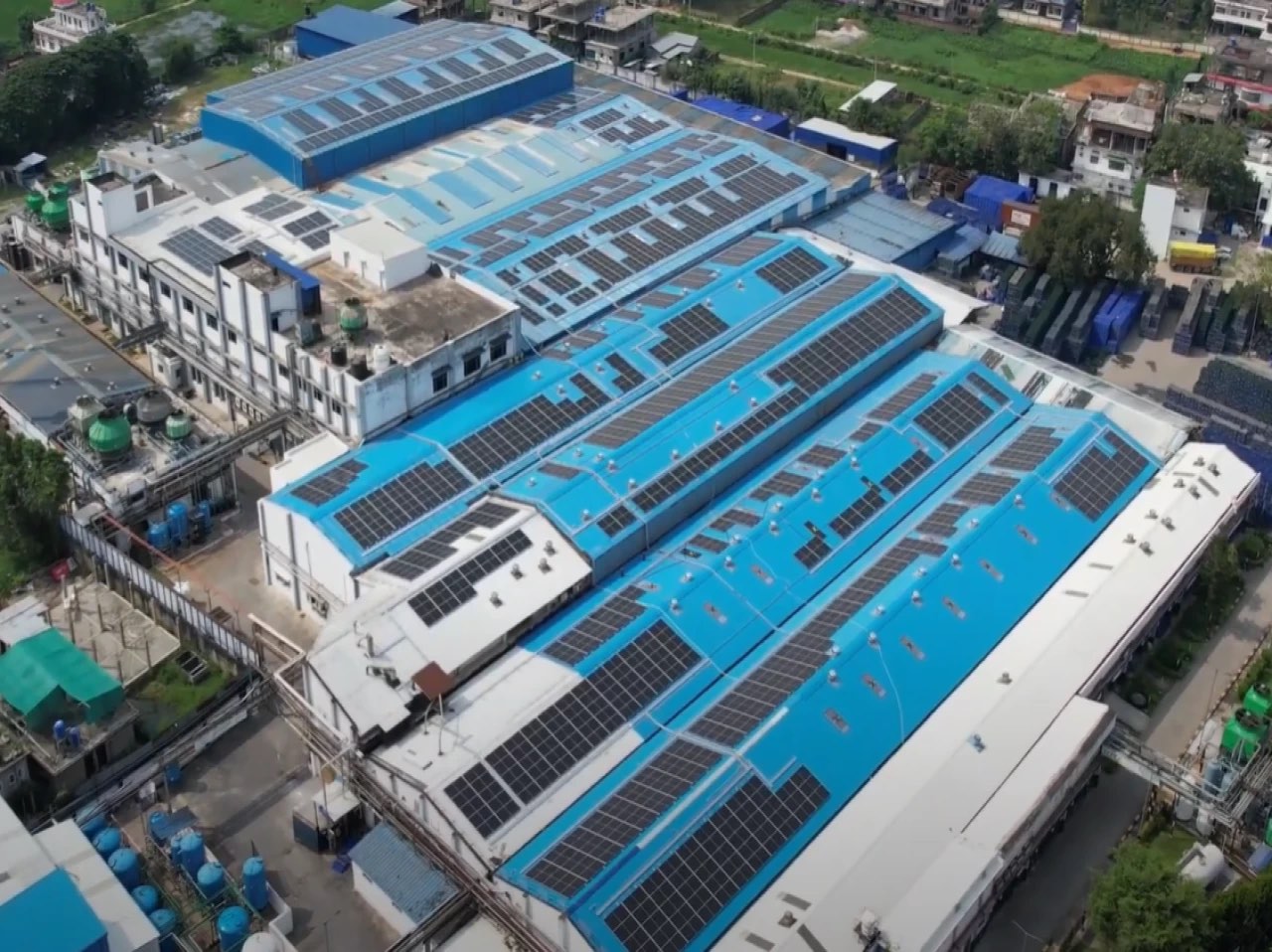 Aerial view of the Guwahati plant in Assam, solar modules across blue industrial roofing